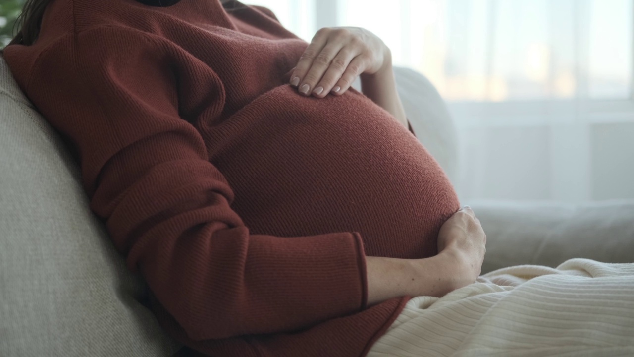 孕妇在沙发上抚摸自己的肚子视频素材