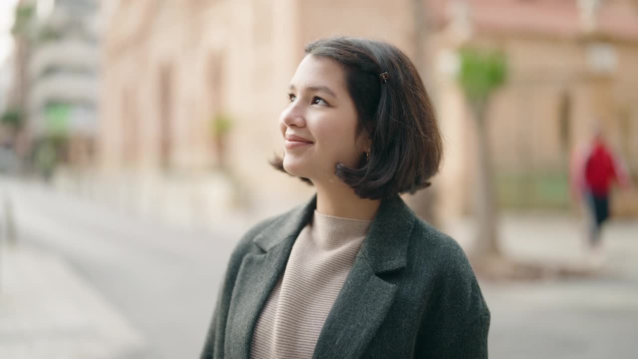 年轻的西班牙女孩微笑着自信地站在街上视频素材