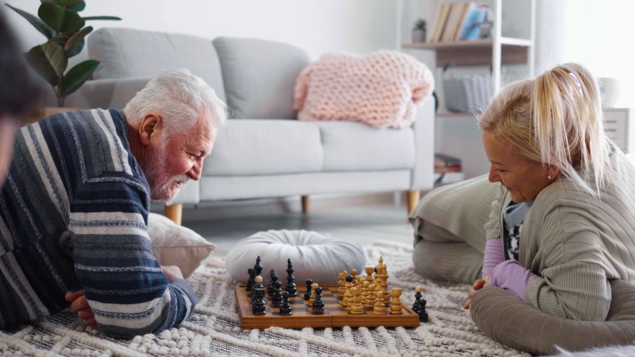 集中精力的爷爷奶奶在家里搬着棋子在棋盘上下棋视频素材