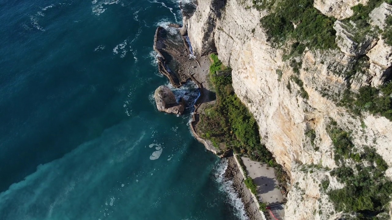 从空中俯瞰，海浪拍打着蓝色海洋中的岩石。海浪在美丽的海滩鸟瞰图无人机。从上方鸟瞰海浪撞击空岩悬崖的景象。视频素材