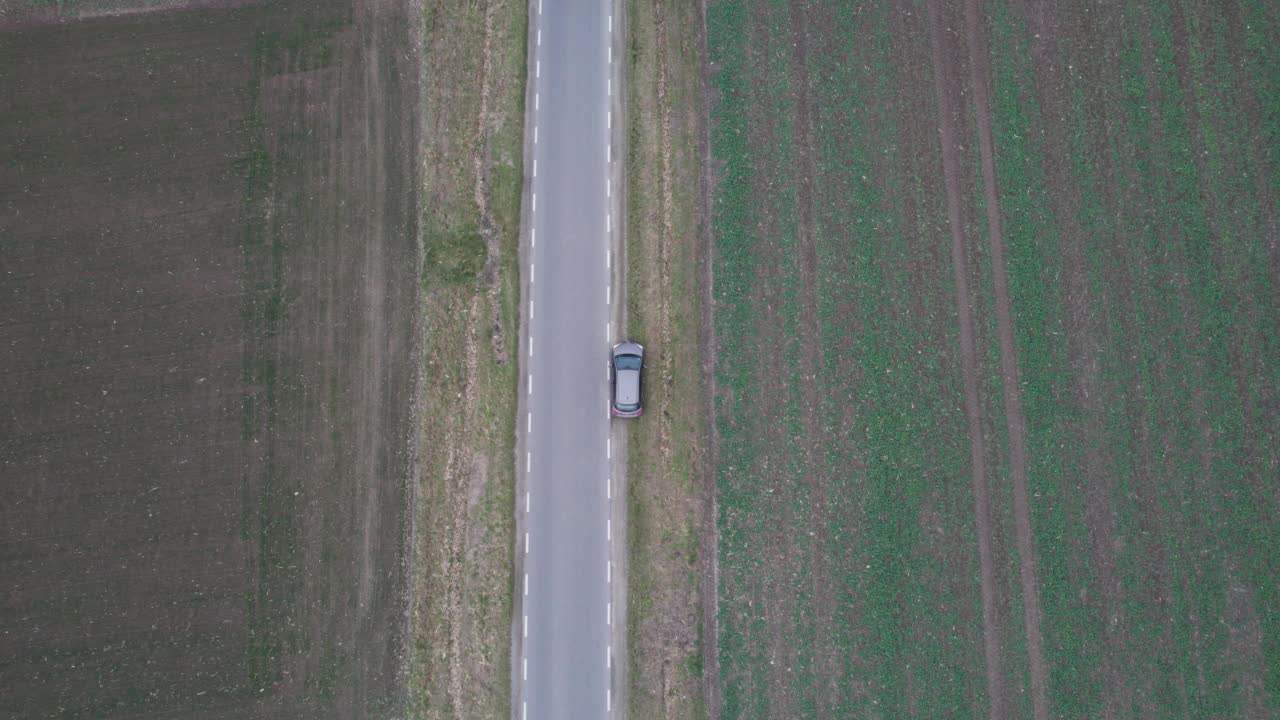 汽车正行驶在穿过田野的道路上，无人机拍下了鸟瞰图。秋天的时候在柏油路上，镜头跟着车走。视频素材