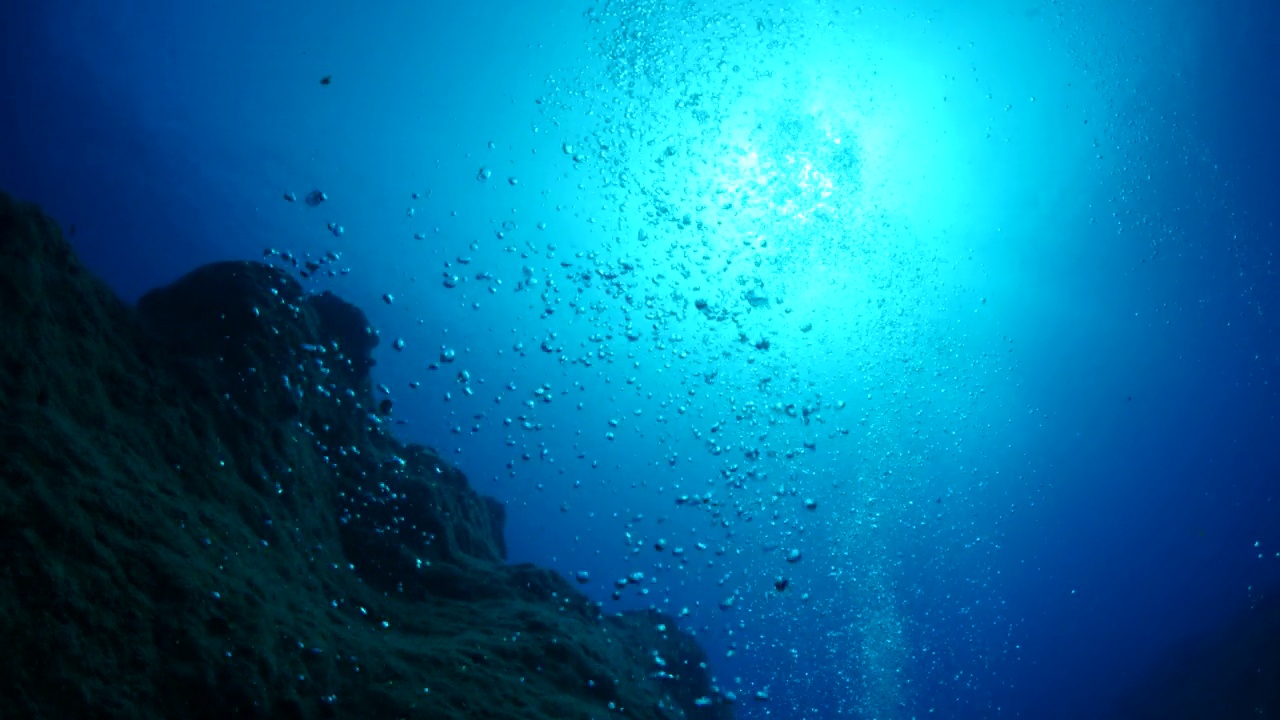 水下接近水面与天空的海洋风景，阳光光束，阳光射线和气泡缓慢放松的海洋背景视频素材