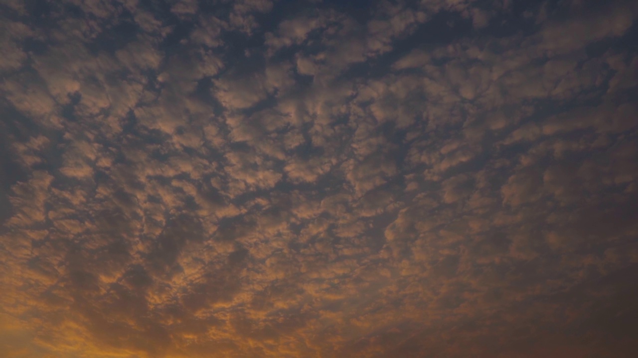 日落时天空中的云的全景式镜头。乌云在日落时形成背景。日落时云变成橘黄色。视频素材