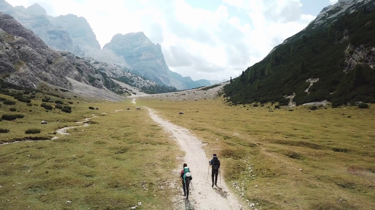 一对夫妇沿着一条穿过意大利白云石山谷的砾石小路徒步旅行。四周是高耸的山峰。石头和原始的景观。偏僻荒凉的地方自由的探索视频素材