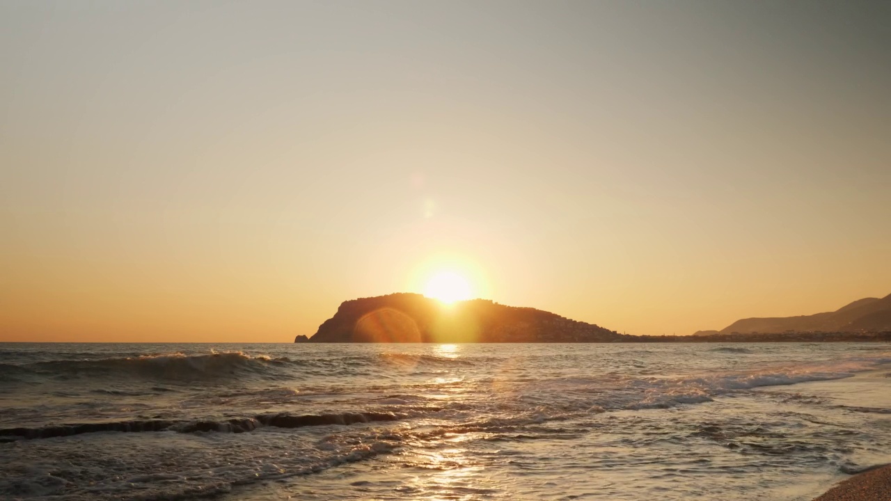 夏季热带海洋景观。海上和岩石海岸线上令人惊叹的彩色日落。海浪到达海岸，拍打着卵石滩。海上地平线上的日落视频素材