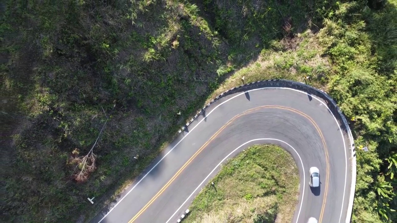 鸟瞰汽车在森林里的乡村道路上行驶。电影无人机拍摄飞行在乡村公路与弯曲的山。视频下载