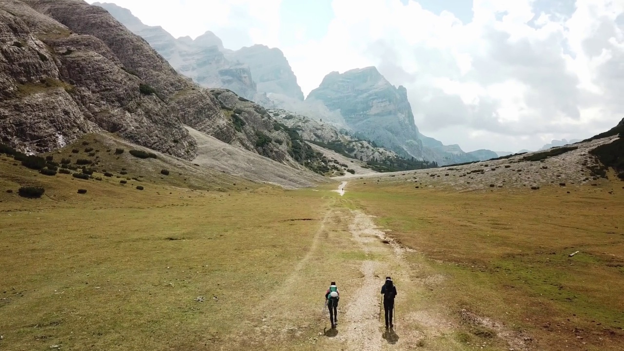 一对夫妇沿着一条穿过意大利白云石山谷的砾石小路徒步旅行。四周是高耸的山峰。石头和原始的景观。偏僻荒凉的地方自由的探索视频素材