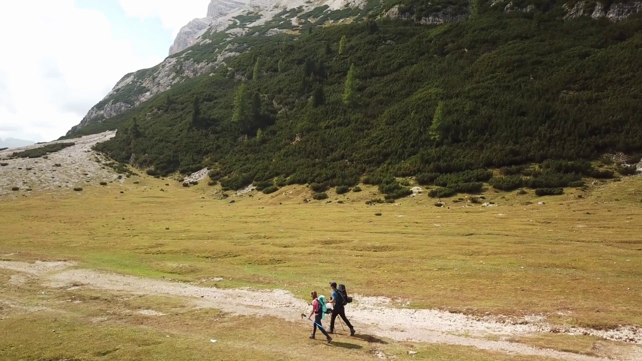 一对夫妇沿着一条穿过意大利白云石山谷的砾石小路徒步旅行。四周是高耸的山峰。石头和原始的景观。偏僻荒凉的地方自由的探索视频素材