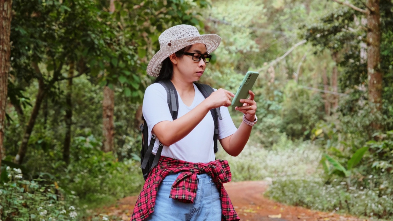 女性旅行者在热带森林背包旅行时使用智能手机定位和导航。视频素材