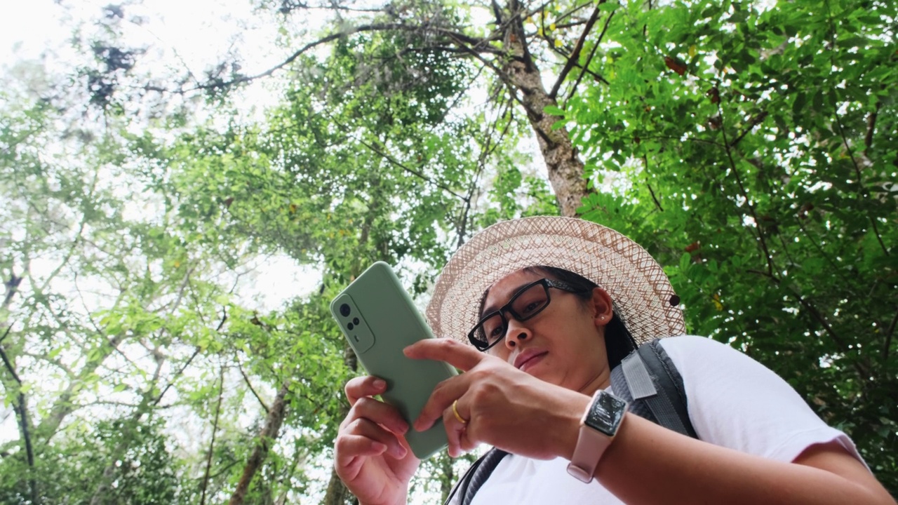 女性旅行者在热带森林背包旅行时使用智能手机定位和导航。视频素材