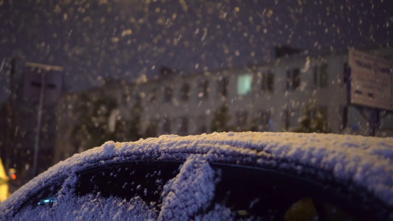 车顶在雪中，背景是夜城。雪花飘落视频素材