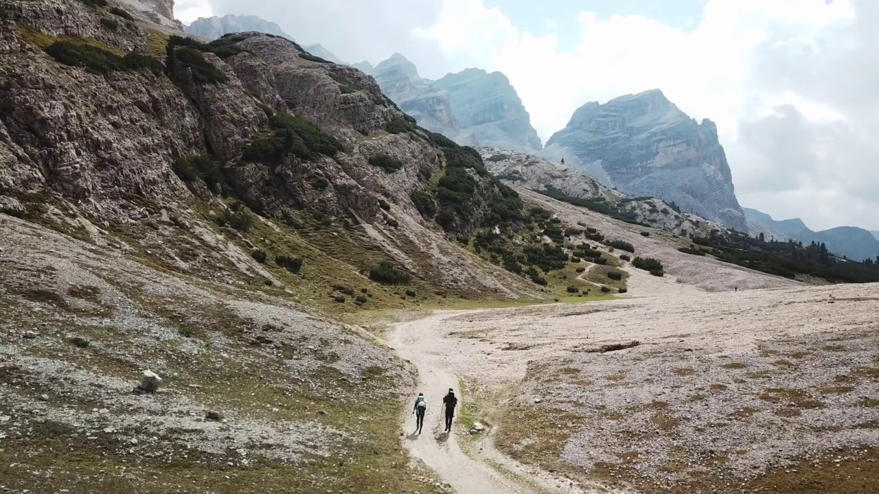 一对夫妇沿着一条穿过意大利白云石山谷的砾石小路徒步旅行。四周是高耸的山峰。石头和原始的景观。偏僻荒凉的地方自由的探索视频素材