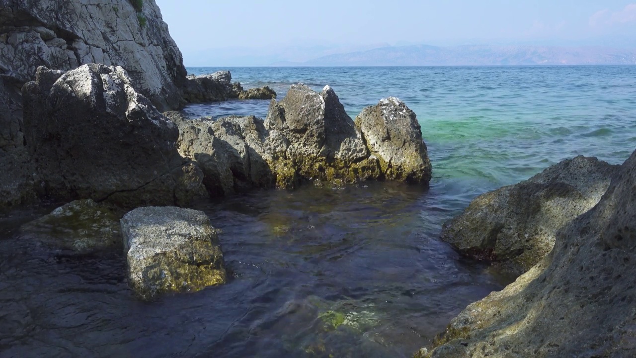 希腊岛屿的岩石海岸和平静的蓝色海面上的海浪视频素材