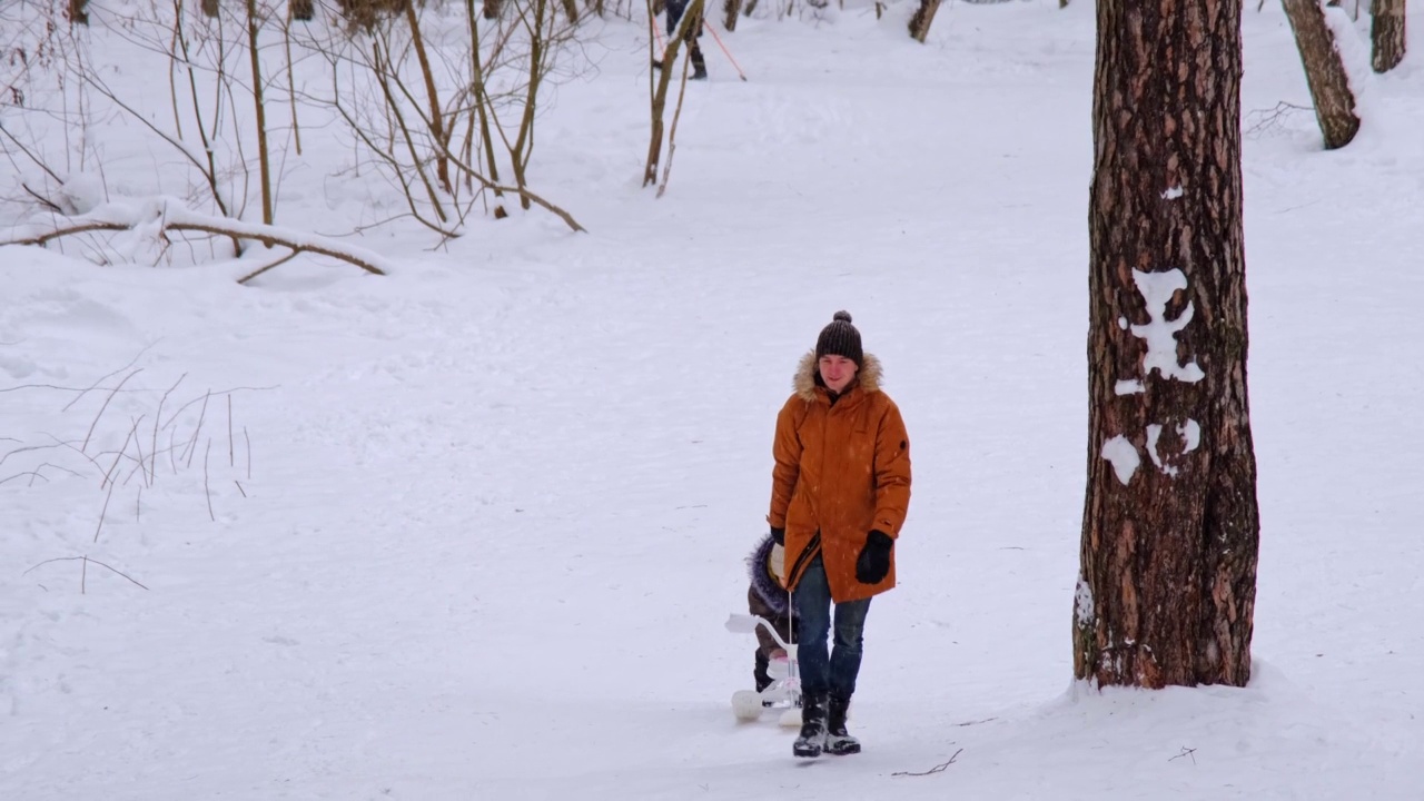 在一个下雪的冬天，爸爸和女儿骑着雪车下山。他们坐在同一个雪橇上。冬季家庭娱乐，情绪高涨视频素材