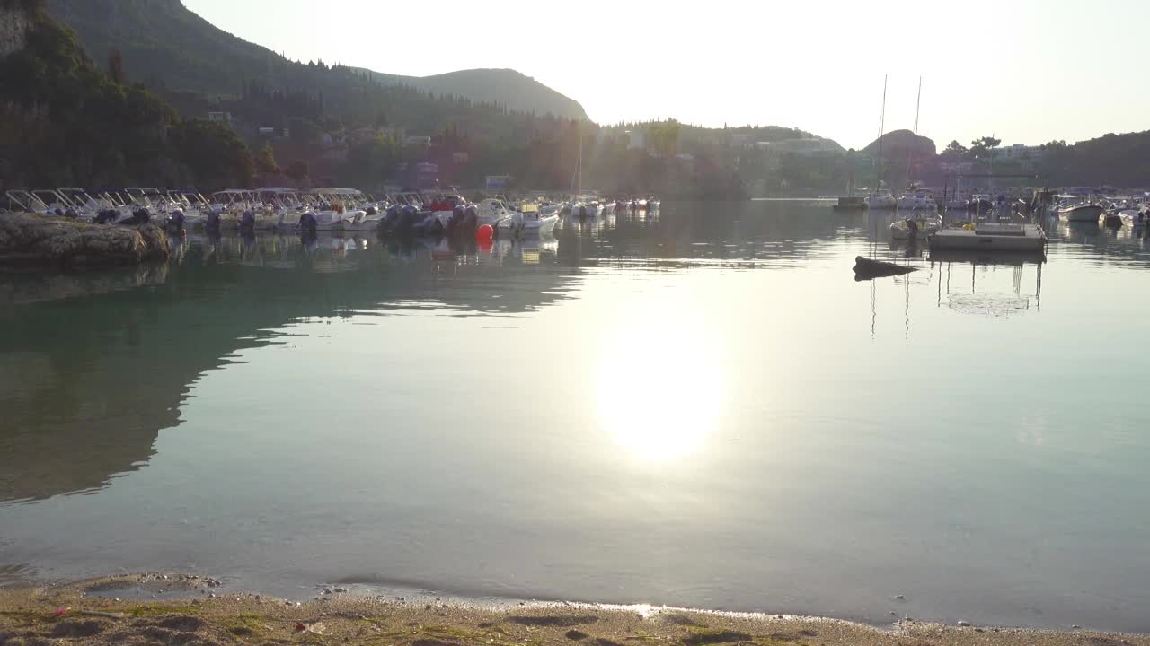 希腊科孚岛，古奥卡斯特海滩的日出美景，椅子、雨伞和停泊的游艇视频素材