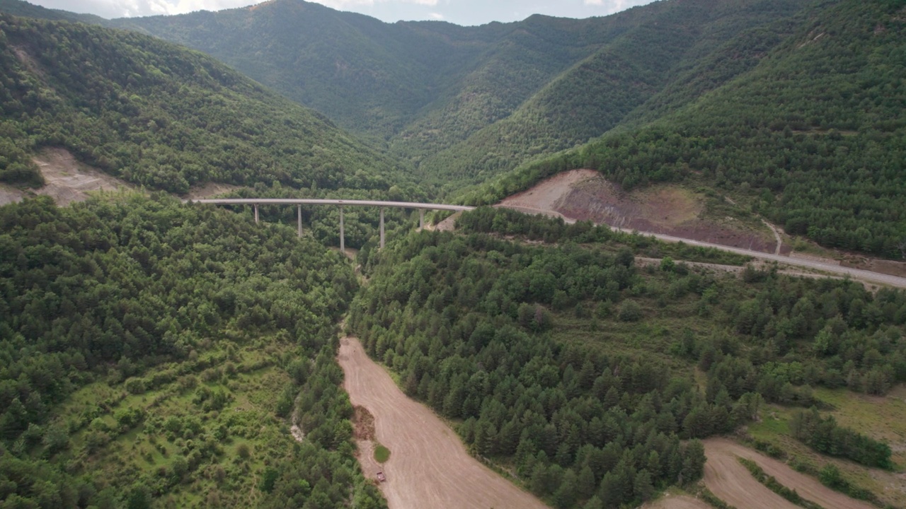 一座桥，一座现代的高架桥，建在山上，有一条三车道的柏油路。钢筋混凝土码头结构的桥梁连接着山林中的两座小山。视频素材