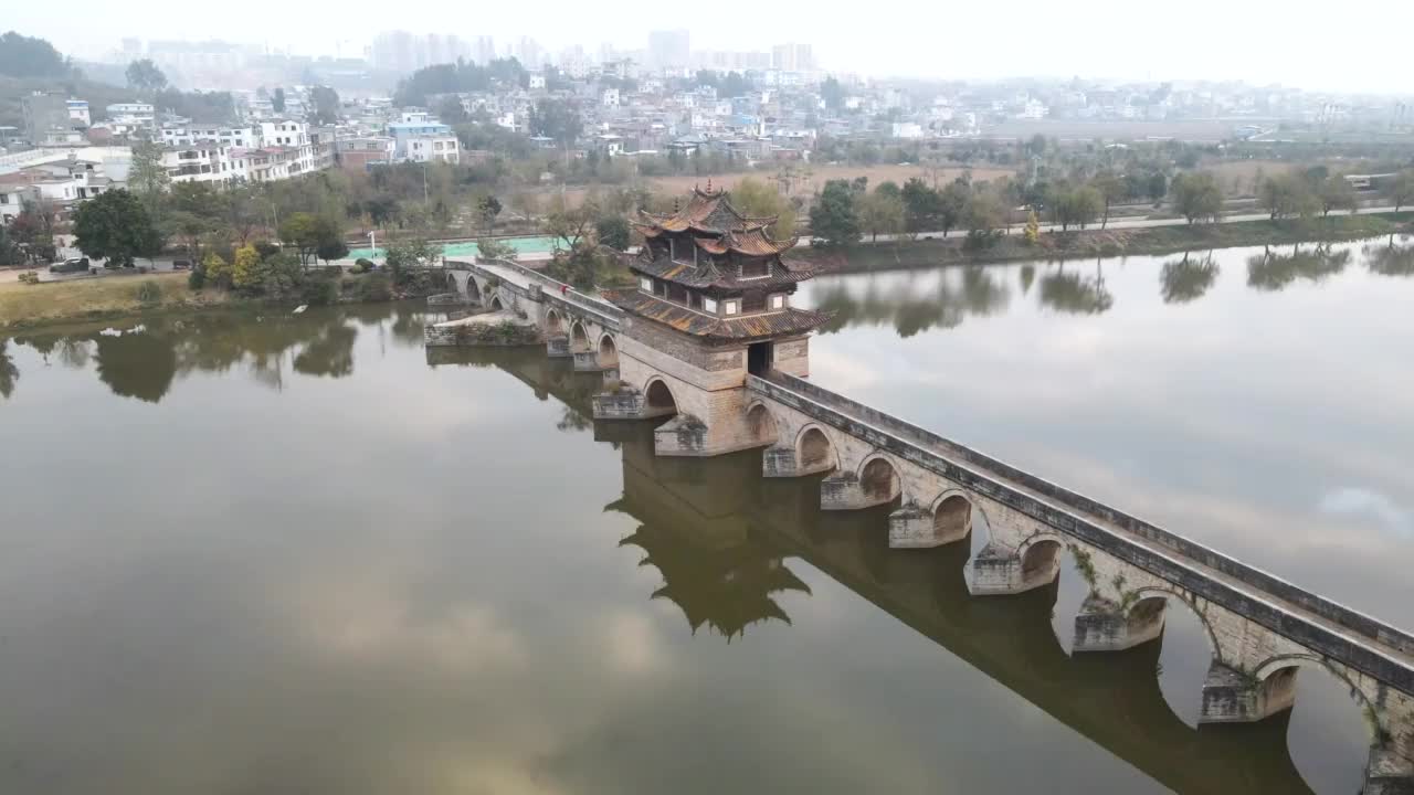 在中国云南省雾蒙蒙的早晨，飞过一座传统的中国风格的桥和一列黄色的火车视频素材