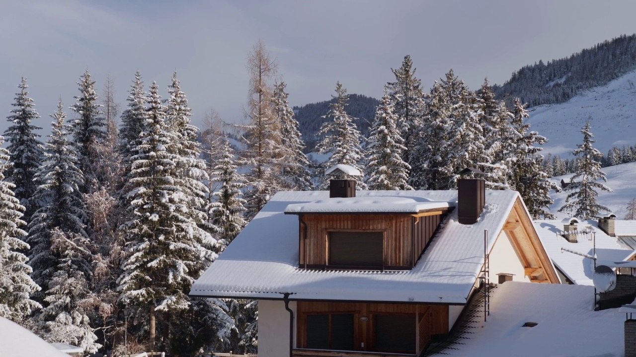 屋顶上有雪的山屋和一场大雪后满是雪的冷杉树，背景是意大利的阿尔卑斯山视频素材