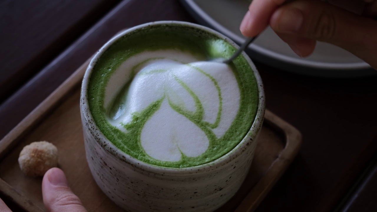 将热腾腾的日本抹茶拿铁泡沫、健康排毒及芳香饮料调配于餐厅。由最好的咖啡师准备的热饮。加奶泡的美味饮料。从上面的观点视频素材