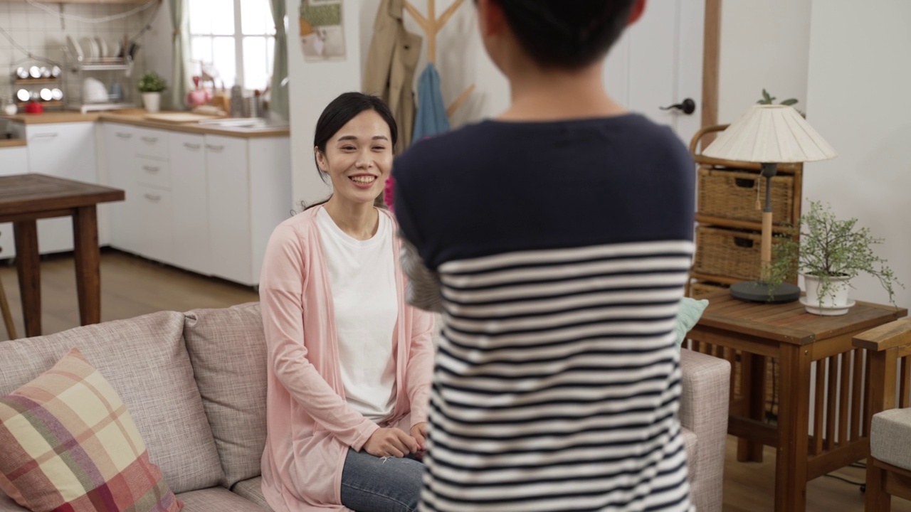 后视镜的亚洲小男孩在母亲节给母亲康乃馨花束在家里。他把花藏在背上，走向微笑的妈妈视频素材