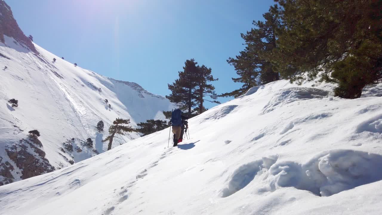 成功的登山队伍是在冬季在高海拔雪山峰顶的山脊上排成一行攀登的队伍视频素材