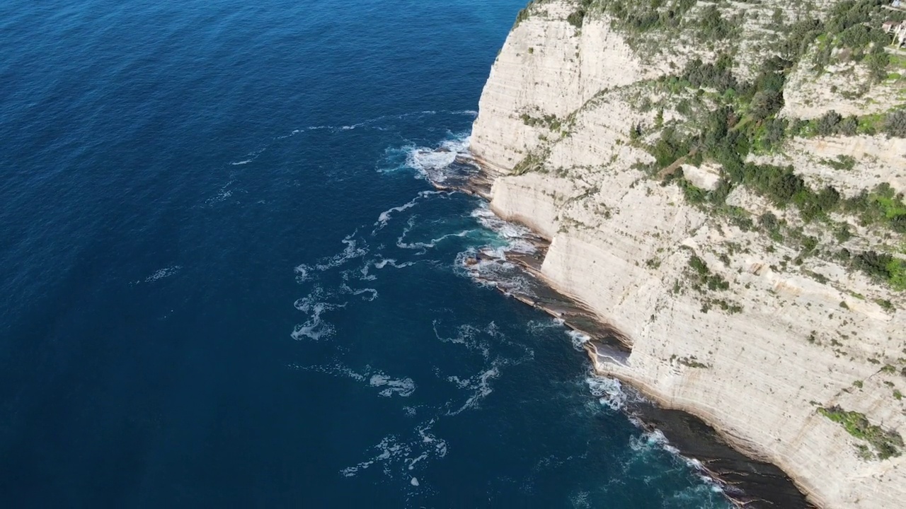 从空中俯瞰，海浪拍打着蓝色海洋中的岩石。海浪在美丽的海滩鸟瞰图无人机。从上方鸟瞰海浪撞击空岩悬崖的景象。视频素材