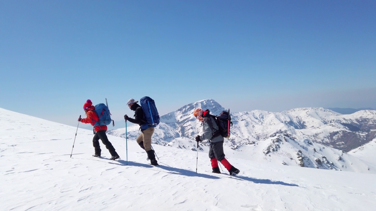 成功的登山队伍是在冬季在高海拔雪山峰顶的山脊上排成一行攀登的队伍视频素材