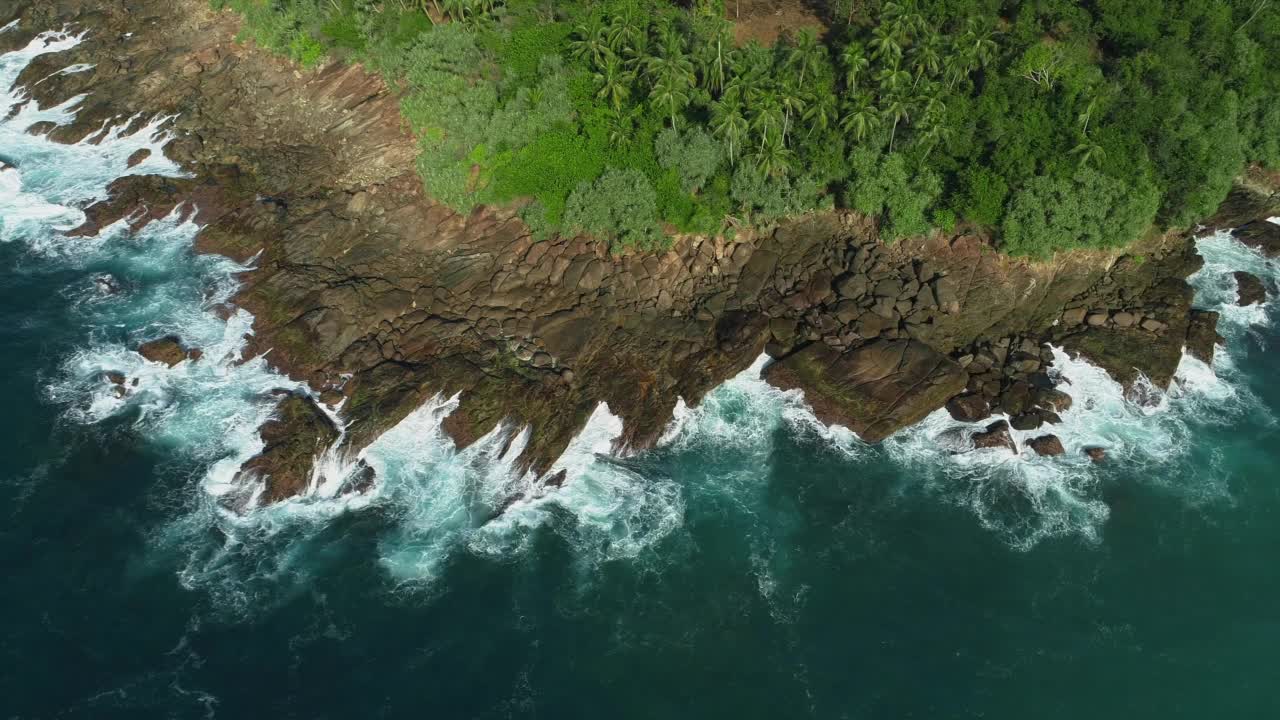 在岩石海岸周围飞行。绕着石头斗篷飞行。波浪拍打着石岬。视频素材