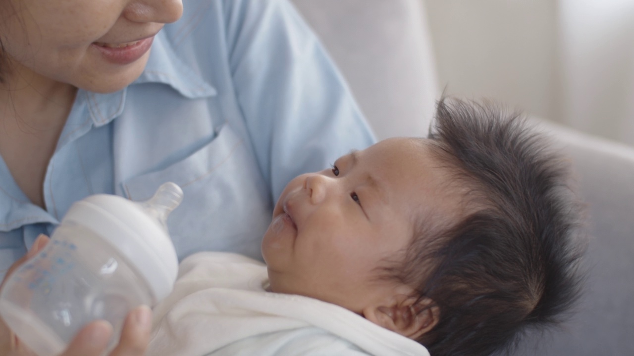 亚洲母亲用奶瓶喂她的新生婴儿在她的怀里。视频素材