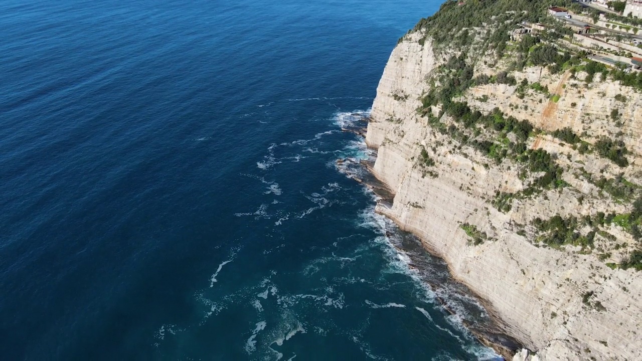 从空中俯瞰，海浪拍打着蓝色海洋中的岩石。海浪在美丽的海滩鸟瞰图无人机。从上方鸟瞰海浪撞击空岩悬崖的景象。视频素材