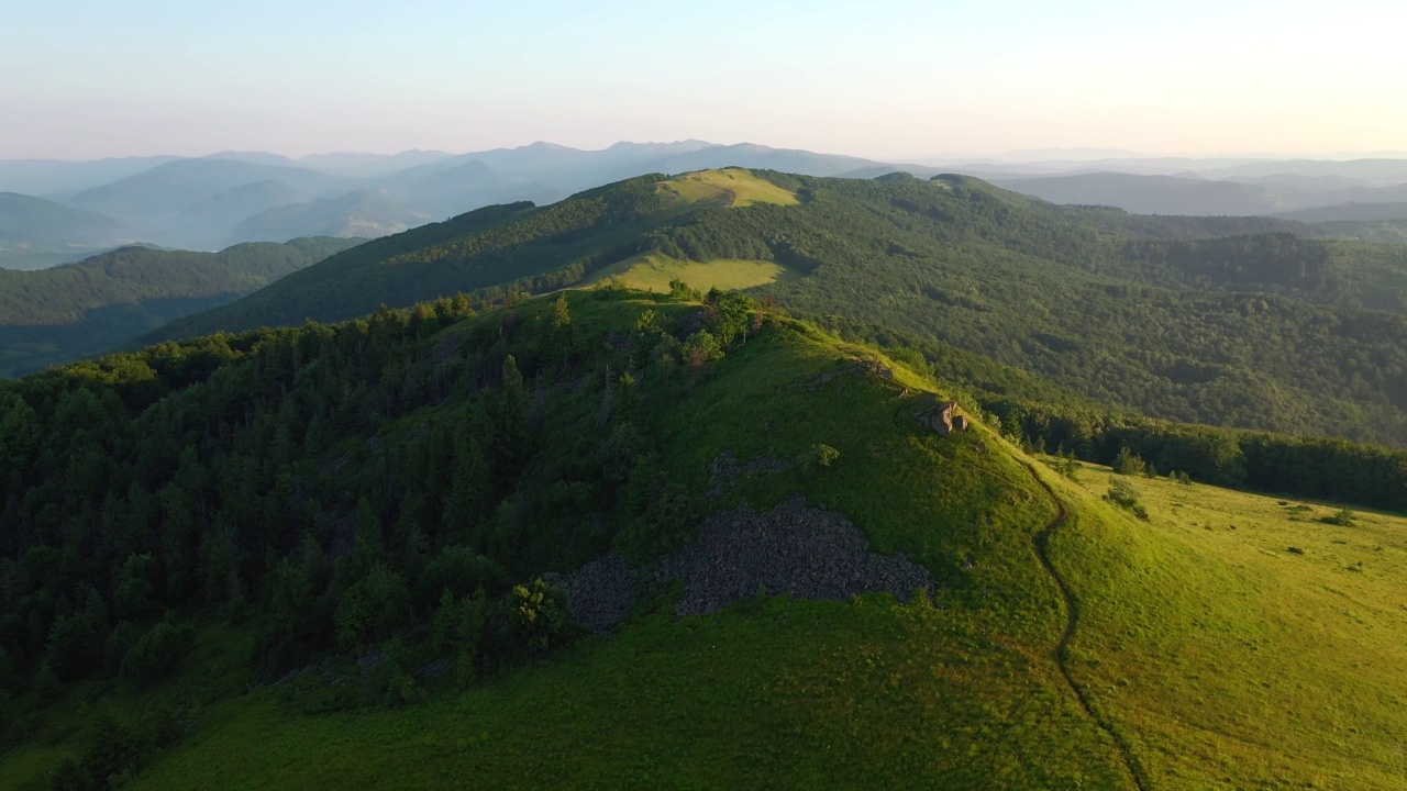 一架无人机飞过高山高地的绿色草地。视频素材