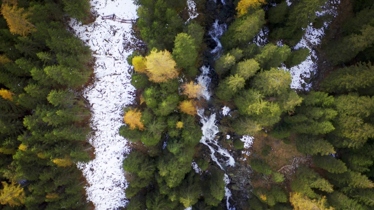 在一个阳光明媚的秋日里，航拍的风景雪景全景上的湖与五颜六色的橙色和红色的树在山上。视频素材