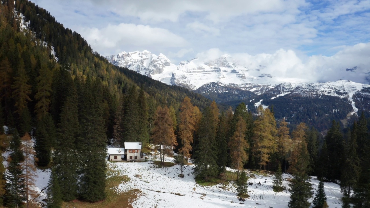 在一个阳光明媚的秋日里，航拍的风景雪景全景上的湖与五颜六色的橙色和红色的树在山上。视频素材