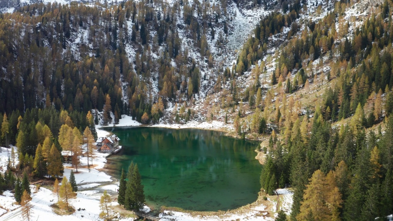 在一个阳光明媚的秋日里，航拍的风景雪景全景上的湖与五颜六色的橙色和红色的树在山上。视频素材