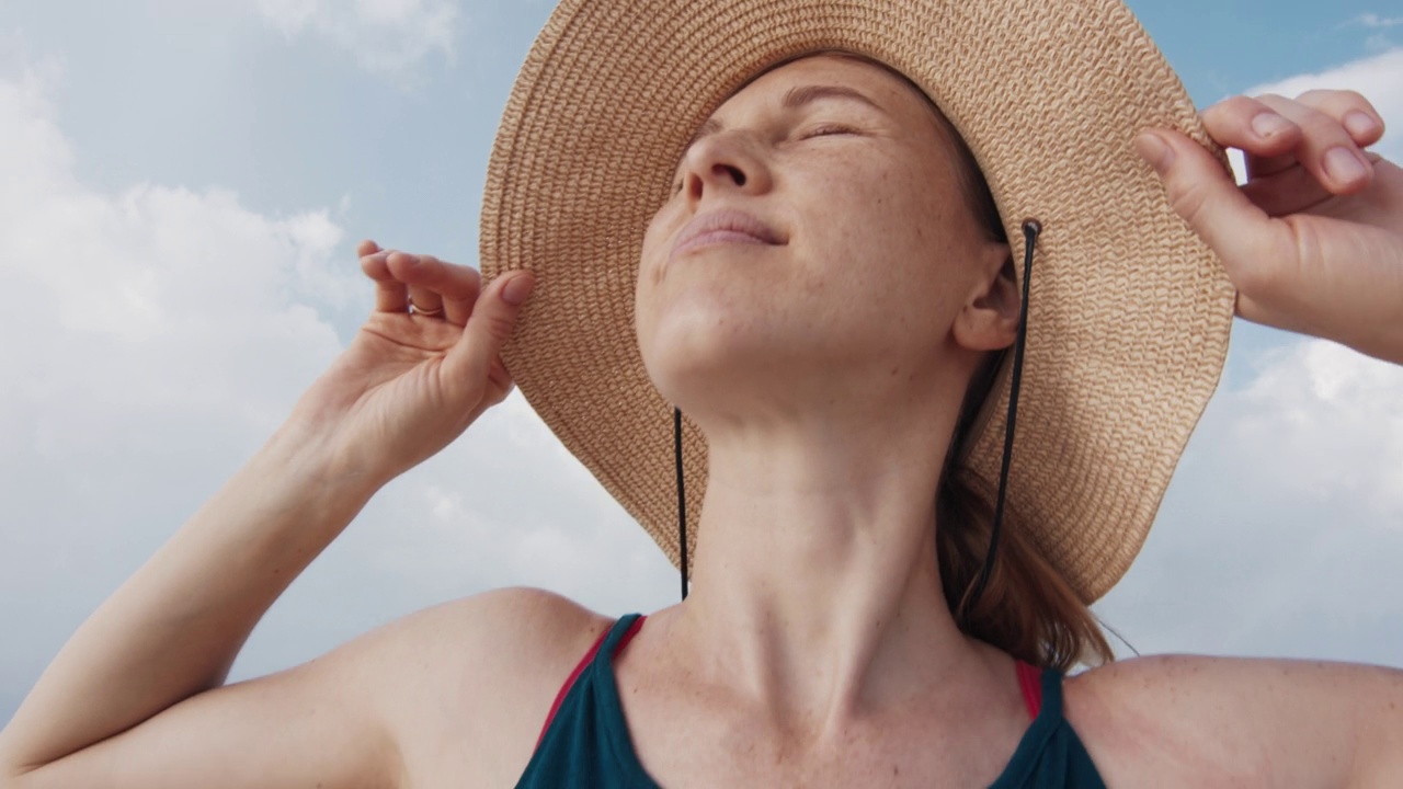 一个戴草帽的女人在海滩上休息视频素材