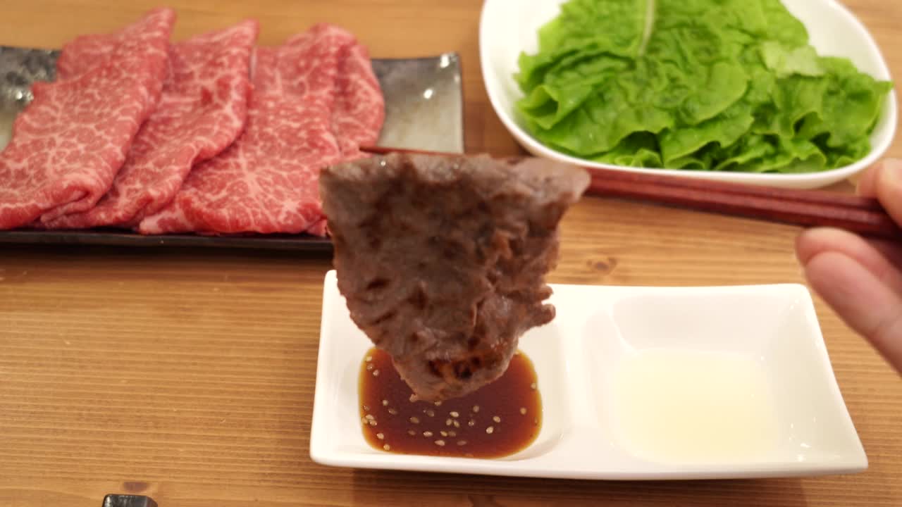 用手将烤好的日本牛肉加入酱汁中视频素材