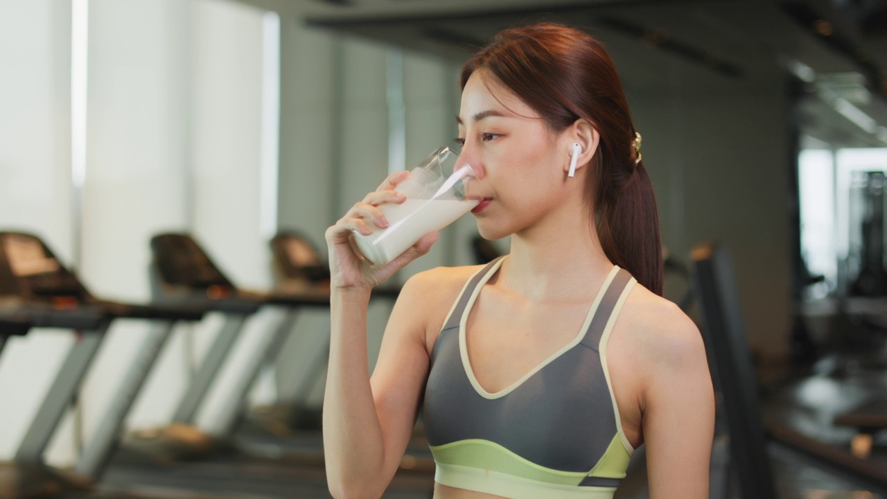 迷人的健美亚洲女人完成锻炼和喝蛋白质牛奶奶昔维生素训练后。健身。健康的生活方式。视频素材