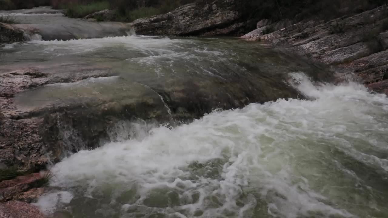 山间河流湍急，水流清澈。鸟瞰图，峡谷之间的河流和春天的大瀑布。视频素材