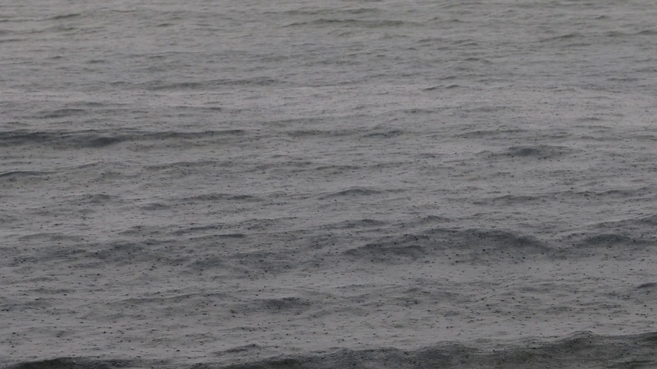 在雨天看到海浪和雨滴飘落的大海。水面慢速运动视频素材