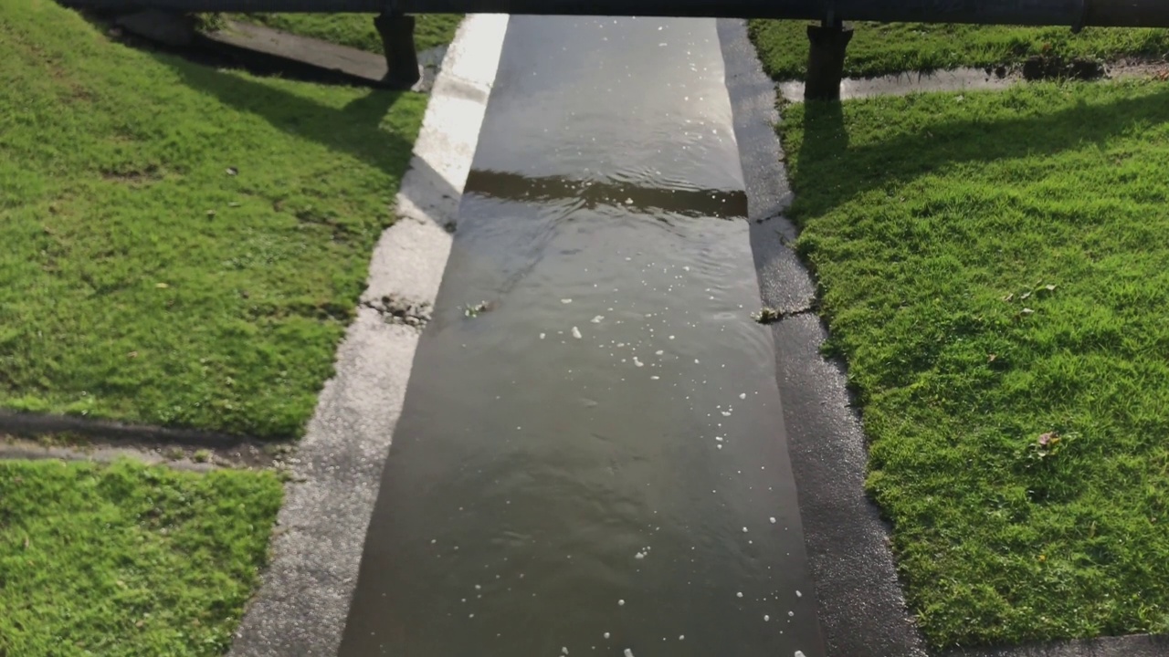 在排水管下的下水道中流动的雨水视频下载