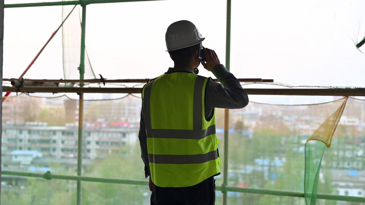 一名男性建筑工人在建筑工地打电话视频素材