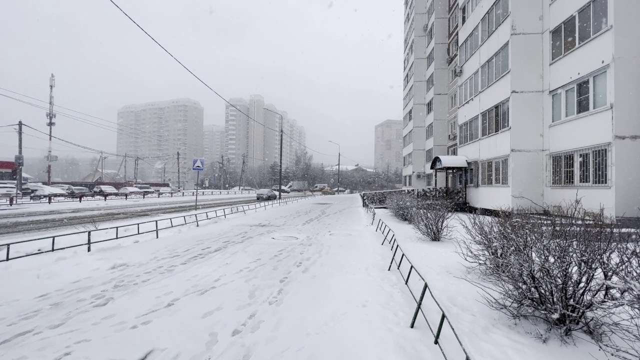 白天城市街道上大雪纷飞。冬天在城市里。白雪覆盖的路面空空如也。视频下载