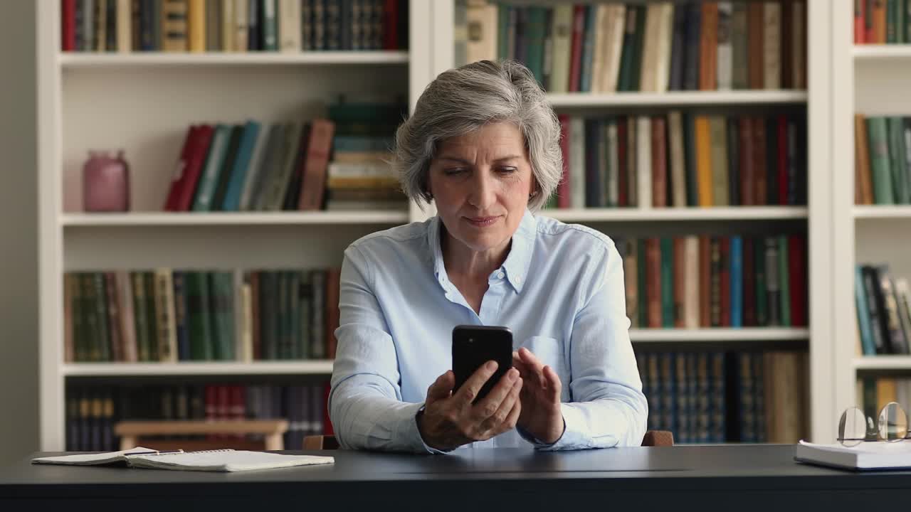 成熟的女人拿着智能手机读愉快的新东西感到兴奋视频素材