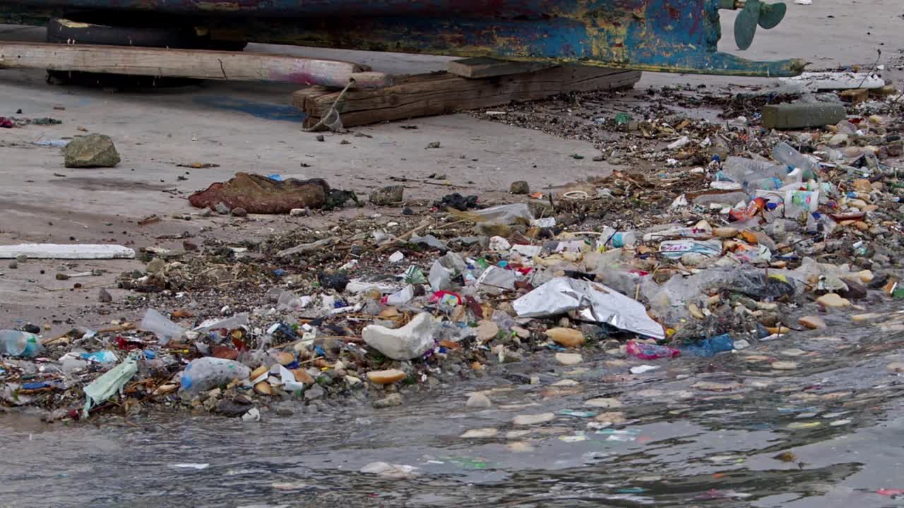 人们扔在海滩上的海洋垃圾会毒害海水视频素材