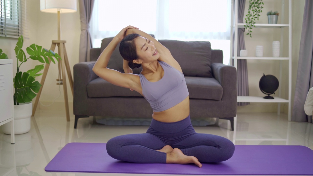 健康的女性正在教授和解释瑜伽。她坐在瑜伽垫上展示她的伸展运动之前，在客厅健康生活方式瑜伽概念瑜伽，缩小拍摄。视频素材