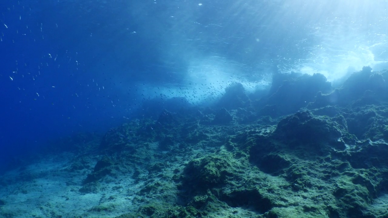 波涛汹涌的海水，波涛汹涌的海水，水下的海浪撞击着岩石，在海面上形成泡沫，形成海洋风景的背景视频素材