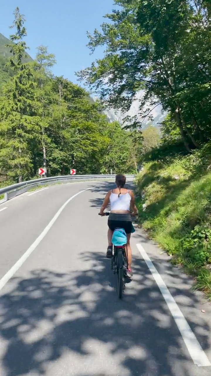 图片:在斯洛文尼亚Bovec，一名女子骑着电动自行车沿着风景优美的道路行驶。视频素材