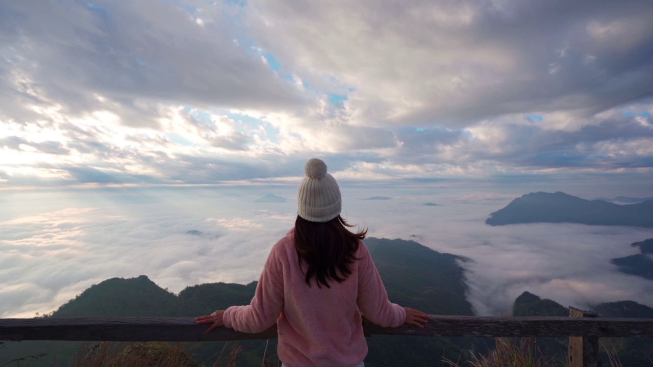 年轻的女旅者在清晨望着山上的日出和海的薄雾，旅行的生活理念视频素材