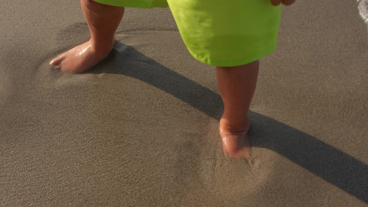 孩子们光着脚站在海浪的沙滩上。洗脚水。视频素材