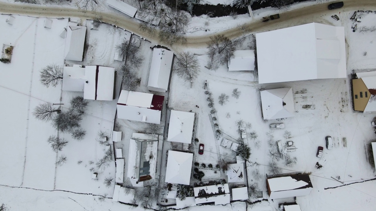 正在滑雪度假村上空飞行4K无人机。空中的冬季景观与小村庄的房子之间的积雪覆盖的森林在寒冷的山脉。视频素材